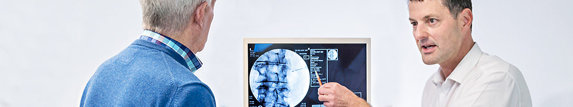 Dr. Knut Bär bespricht Röntgenaufnahmen mit einem Patienten