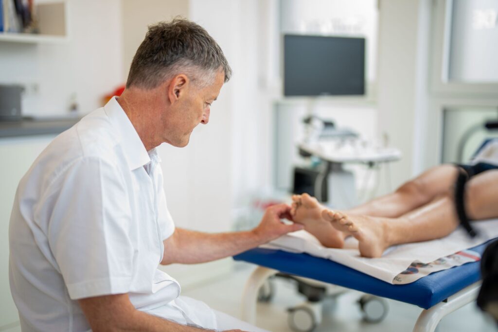 Dr. Knut Bär untersucht das Knie eines Patienten auf der Behandlungsliege